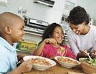 manger sainement, à la maison et en famille : une mère de famille servant ses deux enfants souriants à table.